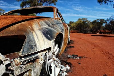 Abandoned car on road against sky