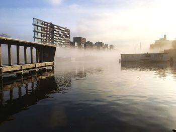 Scenic view of river by city against sky