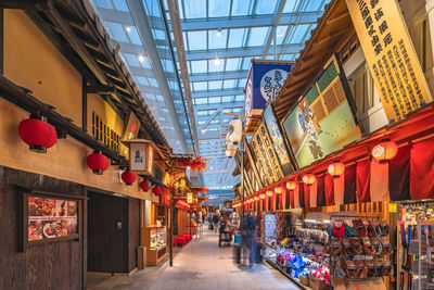 People at illuminated market amidst buildings in city