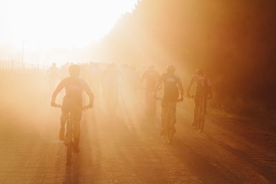 Cyclists against sky during sunset