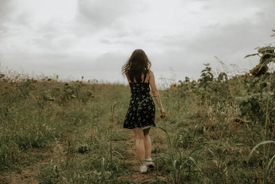 Full length rear view of young woman walking on field