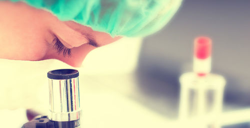 Close-up of scientist looking through microscope