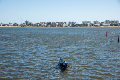 People on boat in sea against clear sky