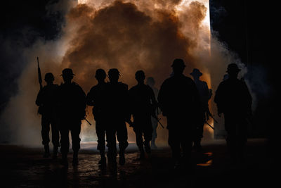 Rear view of silhouette people standing against sky at night