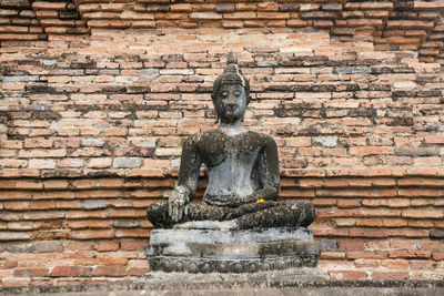 Statue against brick wall