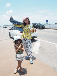 Full length portrait of woman standing with umbrella against sky