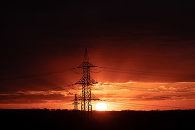 Low angle view of silhouette electricity pylon against sky during sunset