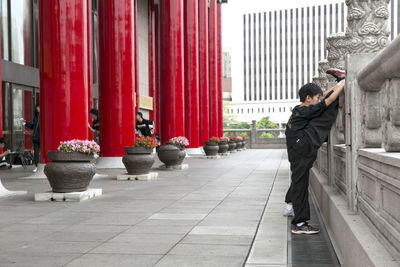 Side view of man stretching on railing in city