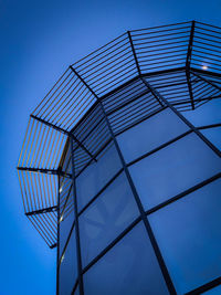 Low angle view of glass building against blue sky