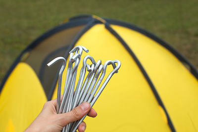 Aluminum stakes for the installation of a tourist yellow tent in the hand close-up. lightweight 