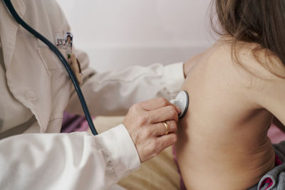 Detail of a pediatric doctor's hand examining a child with a ste