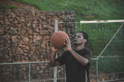 Young man playing basket ball at court
