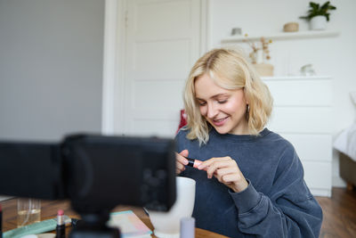 Portrait of young woman using mobile phone at home