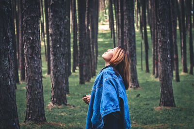 Woman with eyes closed standing in forest