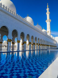 View of swimming pool by building against blue sky