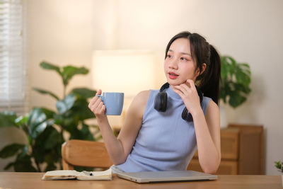 Young woman using mobile phone while sitting at home