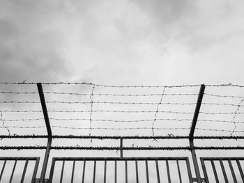 Low angle view of barbed wire fence against sky