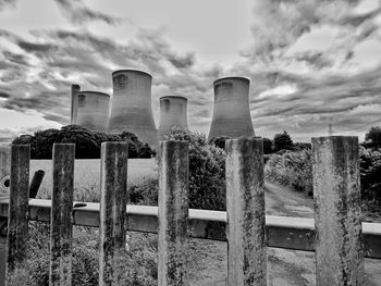 Smoke stacks on grassy field against cloudy sky
