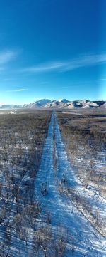 Scenic view of snow covered land against blue sky