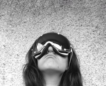 Close-up of woman wearing ski goggles by wall