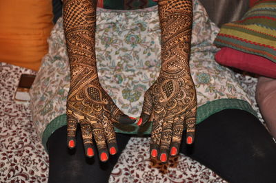 Midsection of woman with henna tattoo on hands