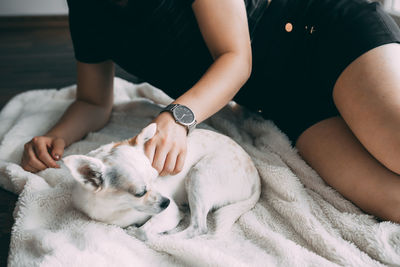 Midsection of woman with dog reclining on bed