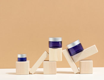 Cosmetic products in a blue glass jar with a gray lid stand on a wooden podium made of cubes. b