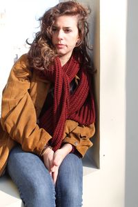 Beautiful young woman sitting in park during winter