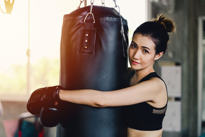 Portrait of young woman embracing punching bag