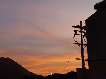 Low angle view of silhouette electricity pylon against sky during sunset