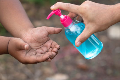 Midsection of person holding bottle in water