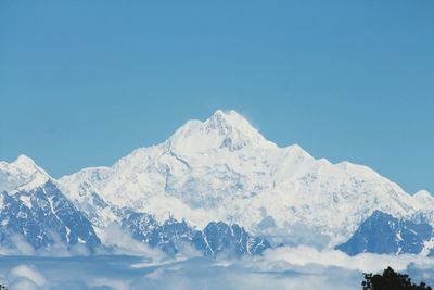 Low angle view of snowcapped mountains against clear blue sky