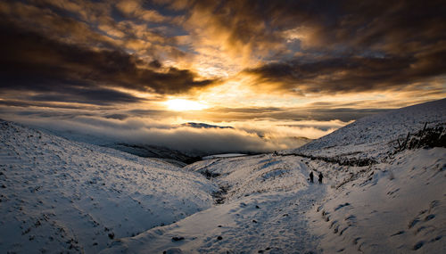 Scenic view of snow covered mountains against sky during sunset