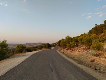 Empty road amidst trees against sky