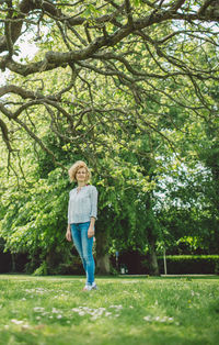 Woman standing on field against trees