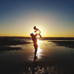 Full length of silhouette man standing on beach against sky during sunset