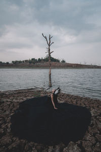 Woman with umbrella on sea shore against sky