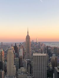 Modern buildings in city against sky during sunset