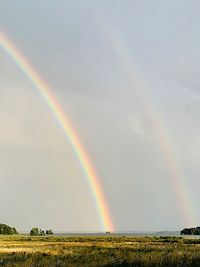 Scenic view of rainbow over field against sky