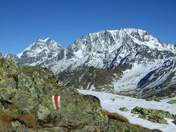 Scenic view of snowcapped mountains against clear blue sky