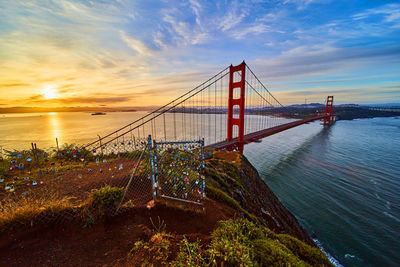 View of suspension bridge over sea against sky during sunset