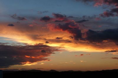 Scenic view of landscape against cloudy sky at sunset