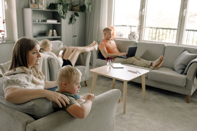 Mother and son with down syndrome watching tv while man and daughter sitting in living room at home