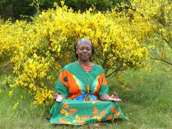 Mature woman meditating on field against plants