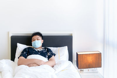 Obese boy wear surgical mask and sleep at home, home isolation