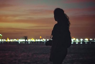 Side view of silhouette woman standing against sky during sunset