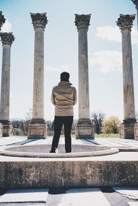 Rear view of person walking in front of pillars