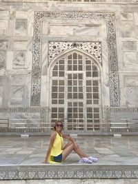 Full length of woman sitting at historic building