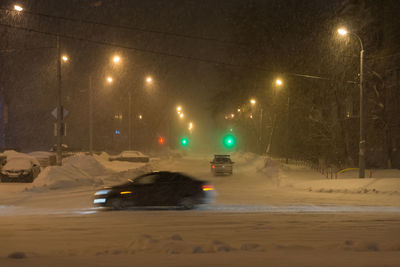 Cars on illuminated street at night during winter
