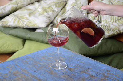 Cropped image of person pouring drink in glass